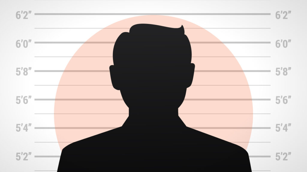 The silhouette of a personal against a criminal line up height backdrop.